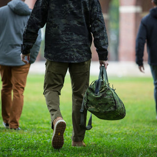 Three men walking with duffle bags wearing OTTE Gear tactical pants.